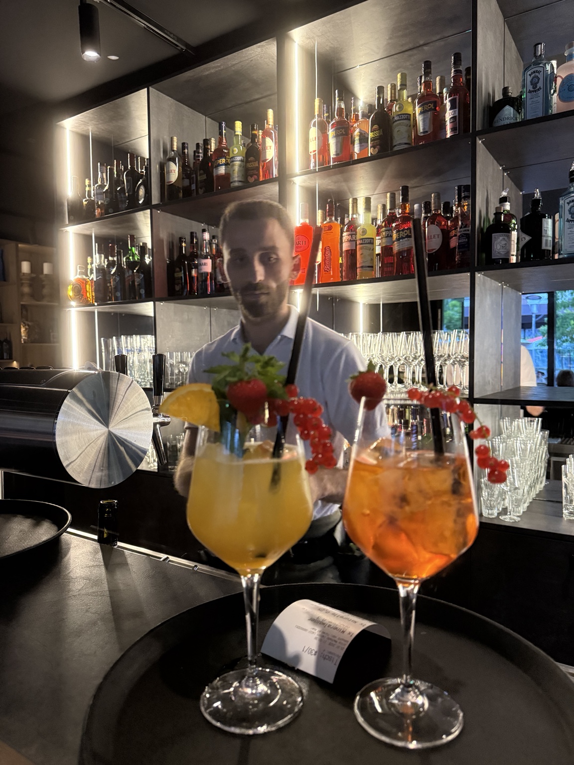Zwei Aperitivo-Cocktails vor der beleuchteten Bar